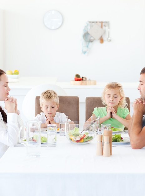 Les parents et leurs enfants en prière pendant leur déjeuner