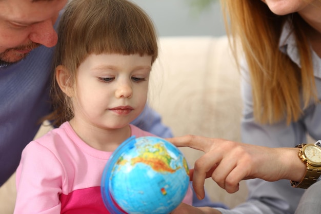 Les parents montrent le globe terrestre à l'enfant en gros plan