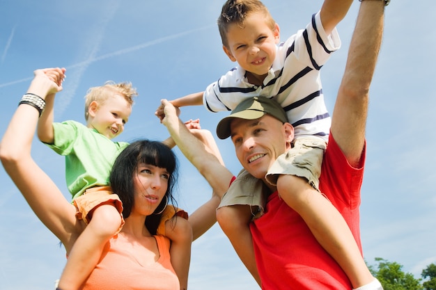 Photo les parents portant leurs enfants sur leurs épaules