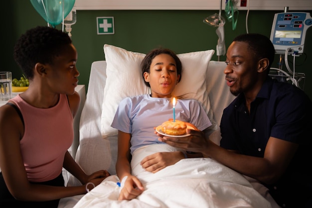 Les parents rendent la visite à l'hôpital spéciale avec des ballons et du gâteau joyeux anniversaire à la fille dans