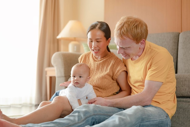 Les parents s'allongent tranquillement et bercent leurs enfants pour déjeuner dans le salon de la maison. Famille, parent, fils, bébé, heureux, concept de mode de vie.