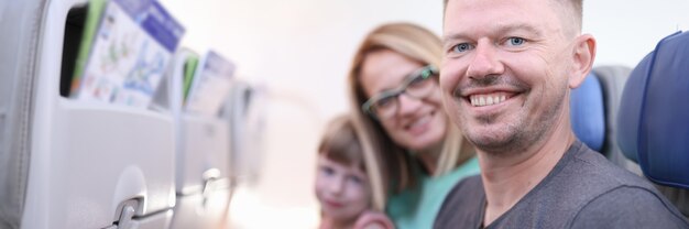 Des parents souriants avec un enfant sont assis dans la cabine de l'avion