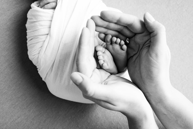 Parents39 paumes Père et mère tiennent les jambes d'un nouveau-né Pieds d'un nouveau-né dans les mains des parents Photo du pied talons et orteils Prise de vue macro en studio noir et blanc
