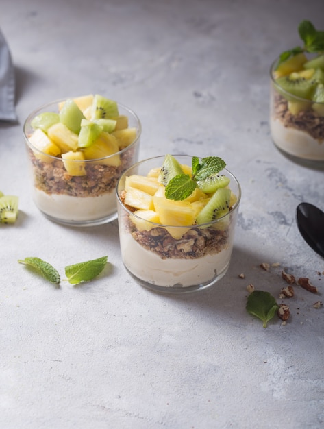 Parfait Au Yogourt Fait Maison Avec Granola, Kiwi, Ananas Et Noix Dans Un Verre Pour Un Petit Déjeuner Sain Sur Fond De Béton