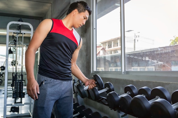 Parfait bodybuilder athlétique athlétique asiatique bras d'entraînement avec haltère sur gym.