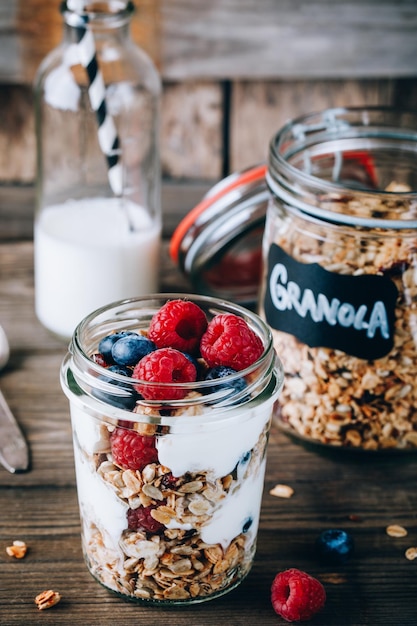 Parfait sain aux bleuets et aux framboises avec du yogourt grec dans un bocal en verre sur fond de bois rustique