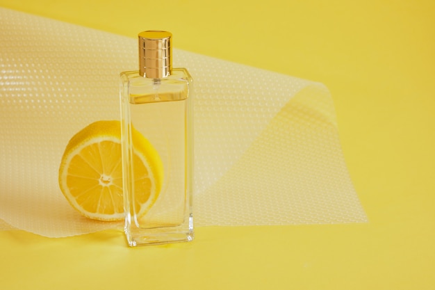 Parfum d'agrumes, parfum au concept de parfum de citron, tranche de citron et bouteille de parfum sur l'espace de copie de fond jaune