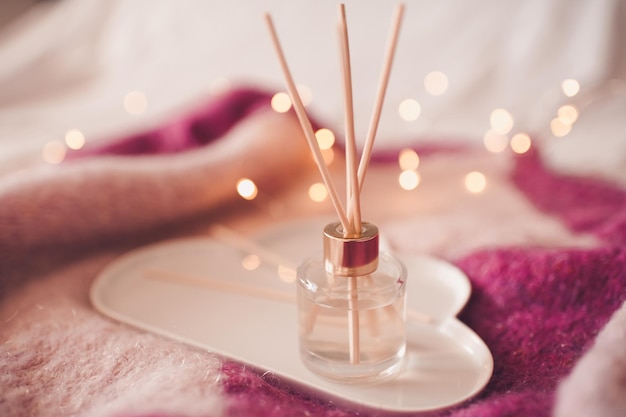 Parfum d'ambiance liquide avec des bâtons d'arôme en gros plan sur une bouteille en verre. Rafraîchissement à domicile.