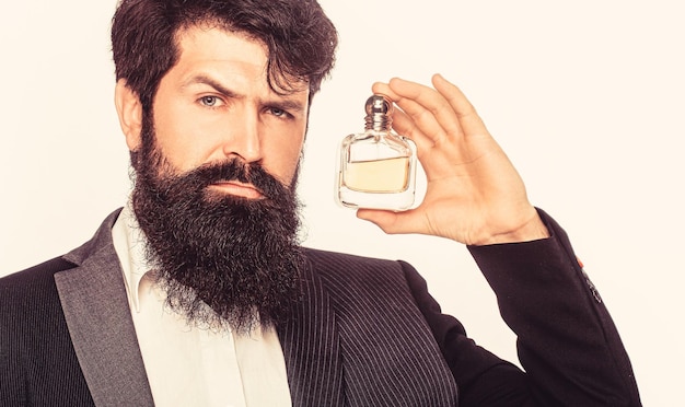 Parfum masculin homme barbu en costume Homme tenant une bouteille de parfum Bouteille de parfum ou d'eau de Cologne parfumerie cosmétiques parfum bouteille d'eau de Cologne mâle tenant de l'eau de Cologne