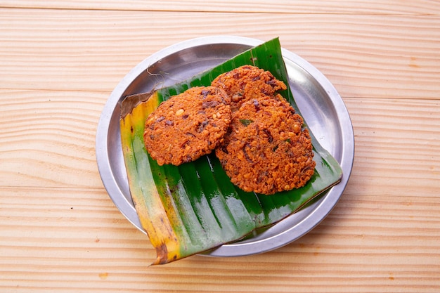 Parippu Vada ou beignets de lentilles dans une plaque d'acier bordée de feuilles de bananier avec fond en bois