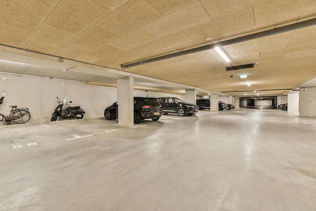 un parking vide avec des motos stationnées dans l'espace et deux voitures stationnées de l'autre côté des garages