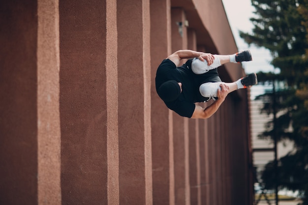 Parkour jeune homme faisant un tour acrobatique et un saut en hauteur