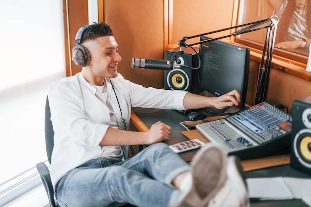 Parle et utilise le micro Le jeune homme est à l'intérieur dans le studio de radio est occupé par la diffusion