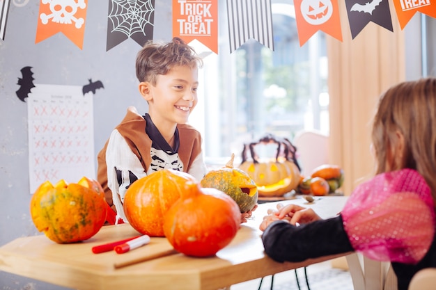 Parler à un ami. Rayonnant drôle de garçon vêtu d'un costume de squelette d'Halloween parlant à son bel ami