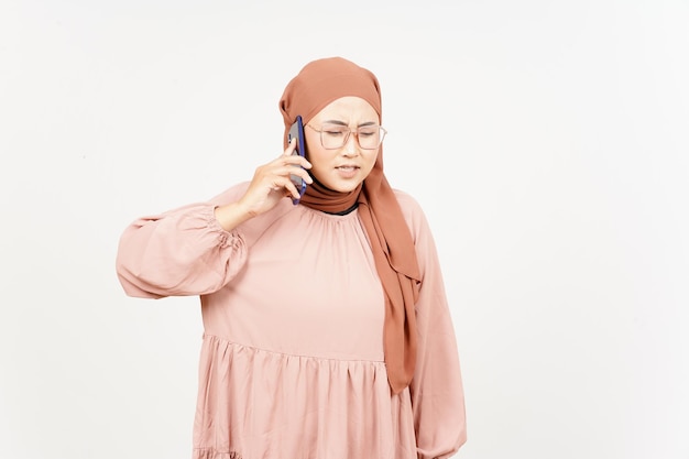 Parler au téléphone et en colère de belle femme asiatique portant le hijab isolé sur fond blanc