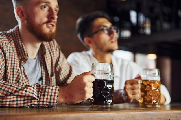 Photo parler les uns avec les autres des gens en vêtements décontractés assis dans le pub