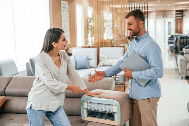 Parler entre eux Couple choisissant le canapé et le lit dans le magasin