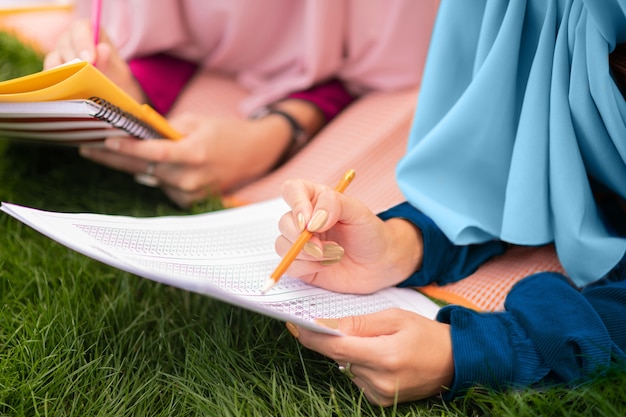 Parler et étudier. Beaux étudiants musulmans intelligents portant le hijab parlant et étudiant ensemble