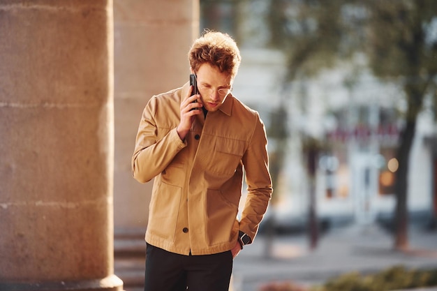 Parler par téléphone Jeune homme élégant dans des vêtements chics formels à l'extérieur de la ville