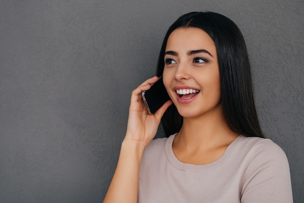 Partager de bonnes nouvelles avec un ami. Jolie jeune femme parlant au téléphone et souriant