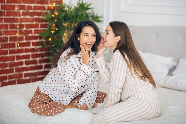 Partager des secrets. Deux jeunes filles en pyjama parlant et souriant