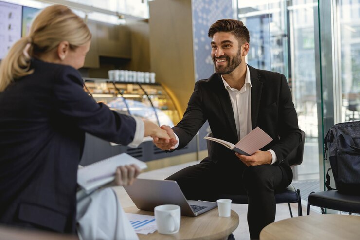 Des partenaires d'affaires souriants se serrent la main après avoir conclu un accord assis dans un café