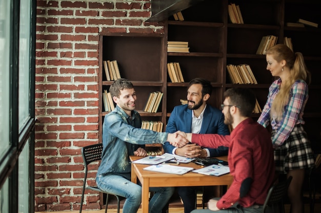 Des partenaires commerciaux fiables se serrent la main après avoir discuté du contrat pour l'espace de travail au bureau