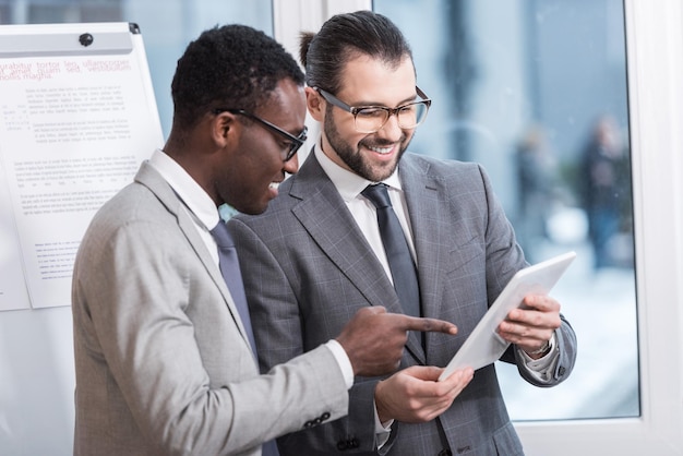 Partenaires commerciaux multiethniques regardant une tablette numérique au bureau