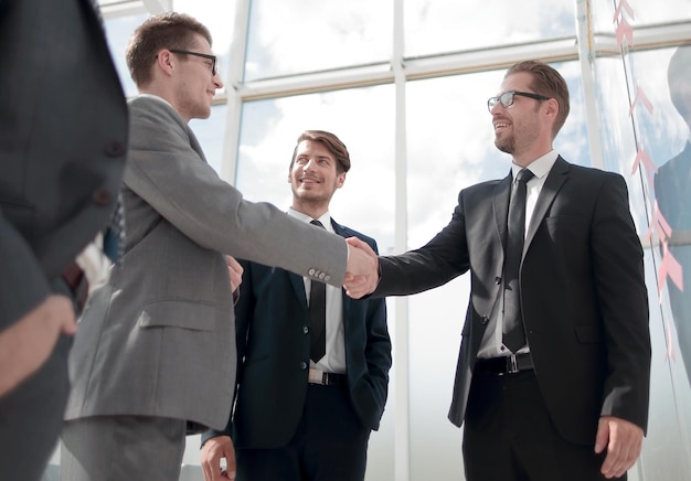 Partenaires commerciaux de poignée de main debout dans un bureau moderne le concept de coopération