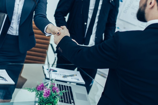 Photo partenaires commerciaux de poignée de main lors de la réunion près du bureau dans un bureau moderne. la photo a un espace vide pour votre texte