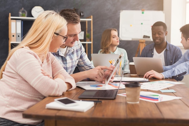 Partenaires commerciaux sérieux travaillant dans un bureau moderne. Deux collègues inquiets discutant d'un nouveau projet tout en travaillant sur un ordinateur portable, espace de copie