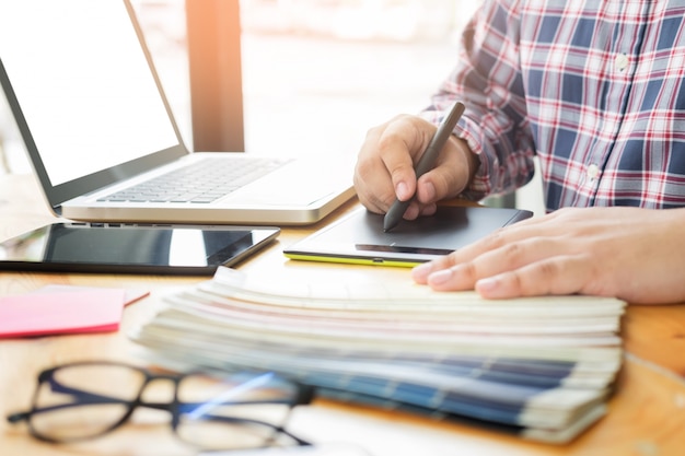 Les partenaires de conception graphique travaillent ensemble à la rénovation et au concept de technologie - sur un ordinateur de bureau et une sélection en utilisant des échantillons de couleurs.