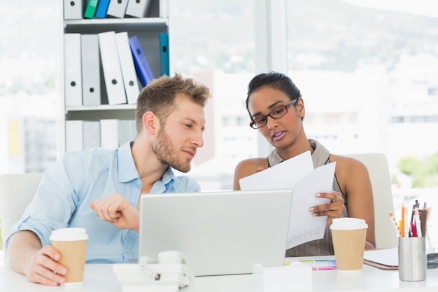 Partenaires travaillant ensemble sur un ordinateur portable au bureau