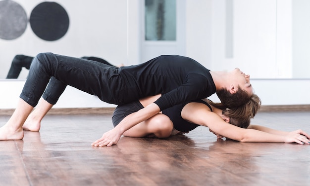 Partenariat de danse. Beau danseur professionnel allongé sur le dos de son partenaire et touchant le sol tout en travaillant ensemble