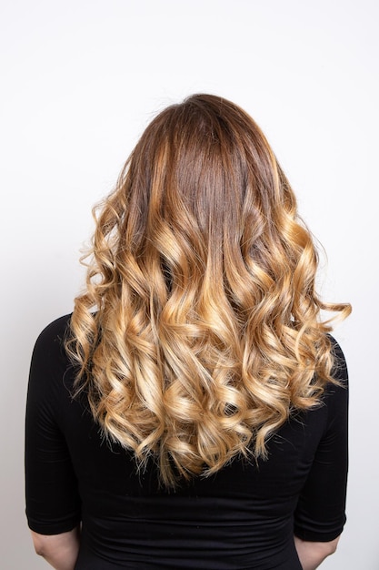 Partie arrière des cheveux d'une jeune femme aux cheveux blonds avec effet de balayage isolé sur fond blanc