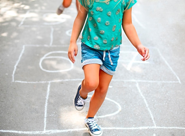 La partie basse de la fille jouant au hopscotch