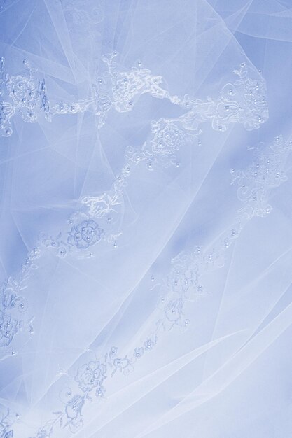 Photo partie d'un beau tissu de tulle en dentelle à broderie bleue ou partie d'une robe de mariée de mariée sur un fond de satin bleu espace pour le texte design vertical