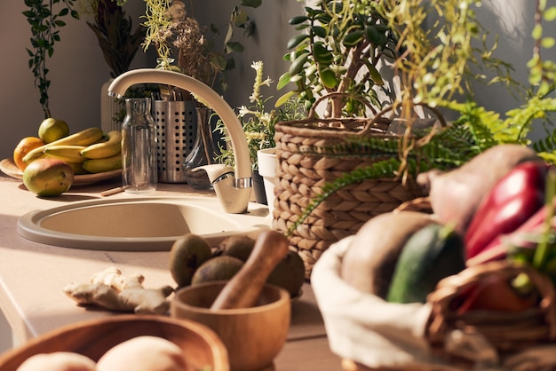 Partie de cuisine ensoleillée avec évier entourée de fruits et légumes frais