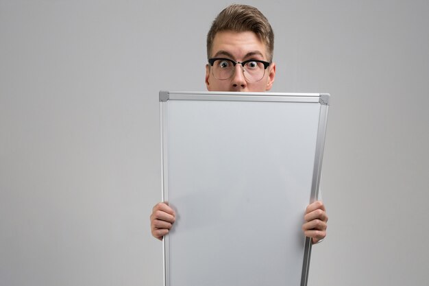 Partie du jeune homme portant des lunettes avec tableau magnétique propre dans ses mains