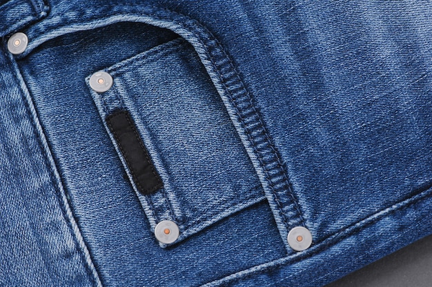 Une partie du pantalon en jean bleu avec poches et rivets, gros plan