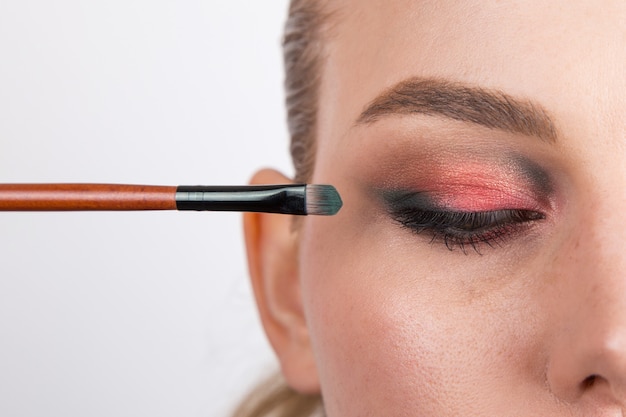 Partie du visage de la jeune fille avec du maquillage des yeux lumineux sur un blanc