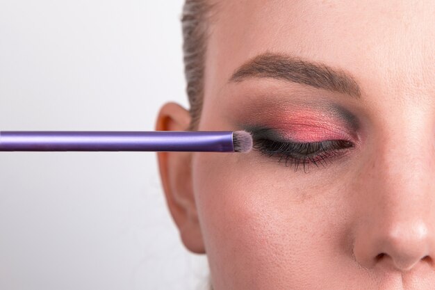 Partie du visage de la jeune fille avec du maquillage des yeux lumineux sur un blanc