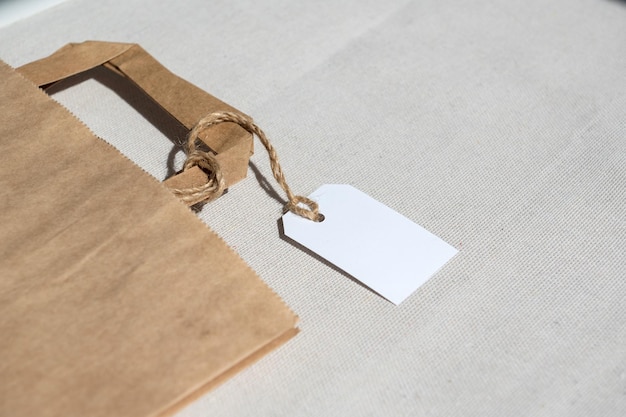 Partie d'un emballage en carton kraft avec une étiquette blanche sur une corde avec poignées pour livraison ou cadeau