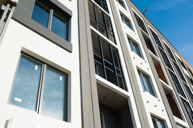 Une partie de la façade avec Windows d'une nouvelle maison aux murs gris contre le ciel