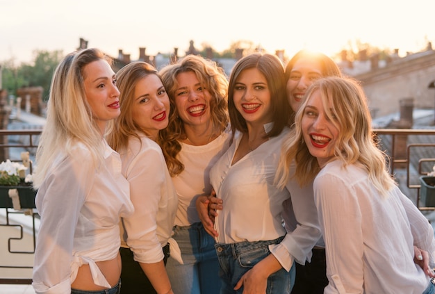 Partie de filles. Amitié de belles femmes sur le balcon ou le toit à l'enterrement de vie de jeune fille au coucher du soleil. Ils portent les mêmes vêtements