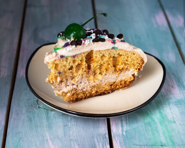 Une partie d'un gâteau fait maison avec du caramel coloré et de la nourriture verte se trouve sur une plaque en céramique légère