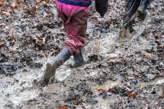 Photo une partie inférieure d'amis portant des bottes en caoutchouc marchant dans une flaque de boue