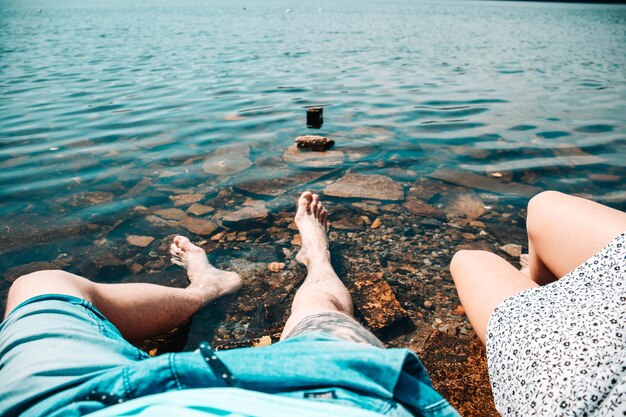 Photo la partie inférieure du couple assis au bord du lac