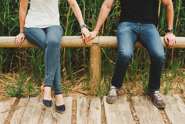 Photo la partie inférieure du couple assis sur du bois