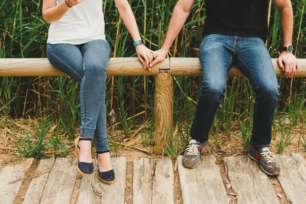 Photo la partie inférieure du couple assis sur du bois